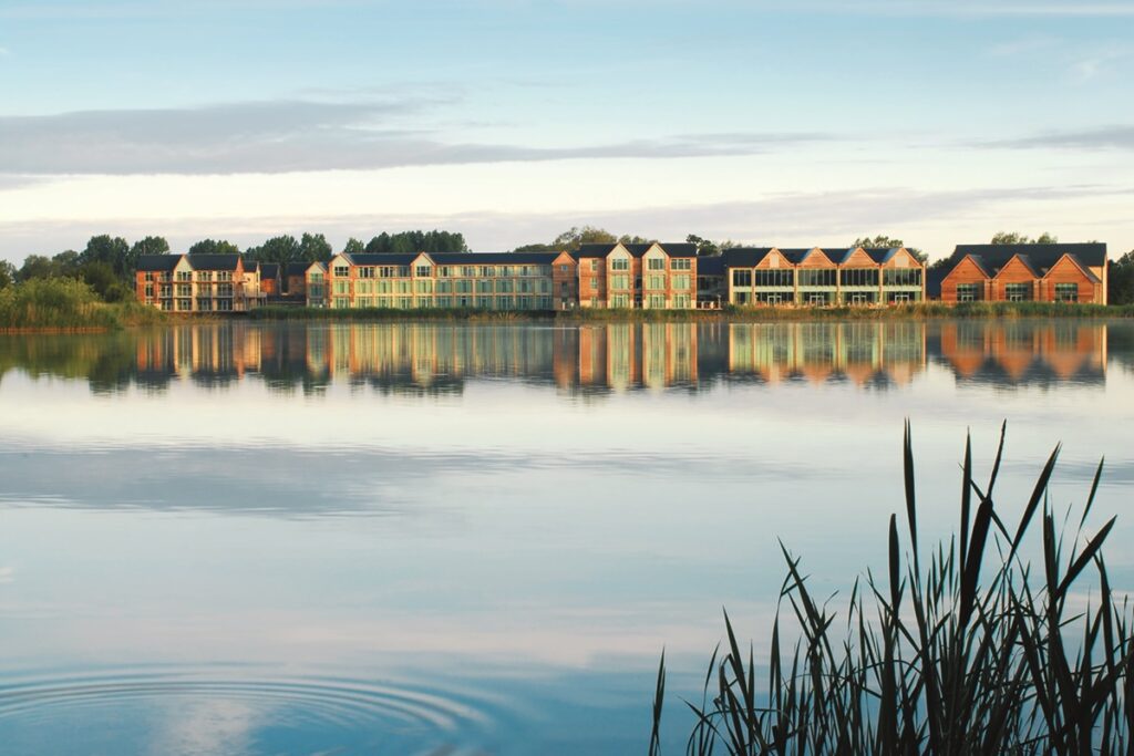 De Vere Cotswold Water Park hotel reflected in the lake