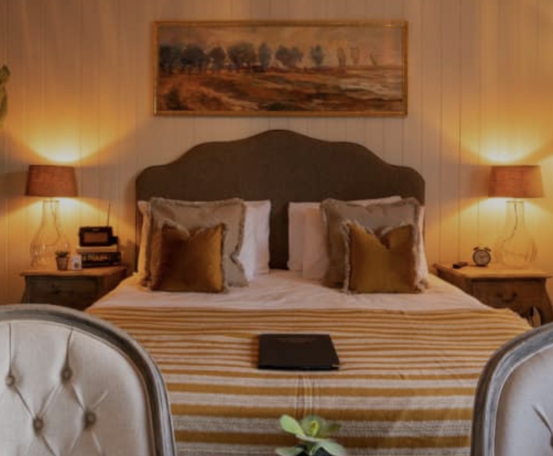 A warmly lit room at The Prince of Burford with a double bed and striped bedspread