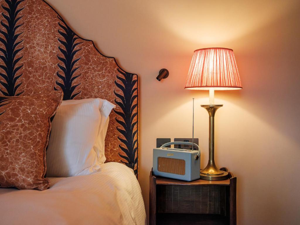 A bedroom at The Stump with a patterned headboard, bedside radio and warm lamplight